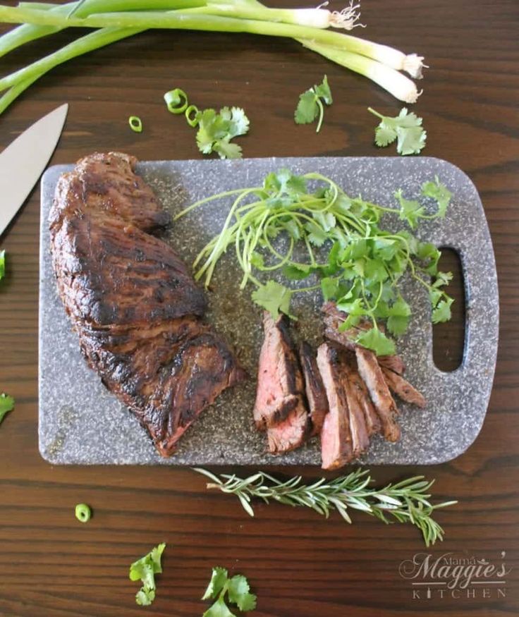 the steak is prepared and ready to be served on the grilling board with fresh herbs