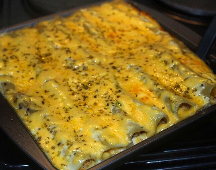 a casserole dish with cheese and other toppings cooking on an oven rack