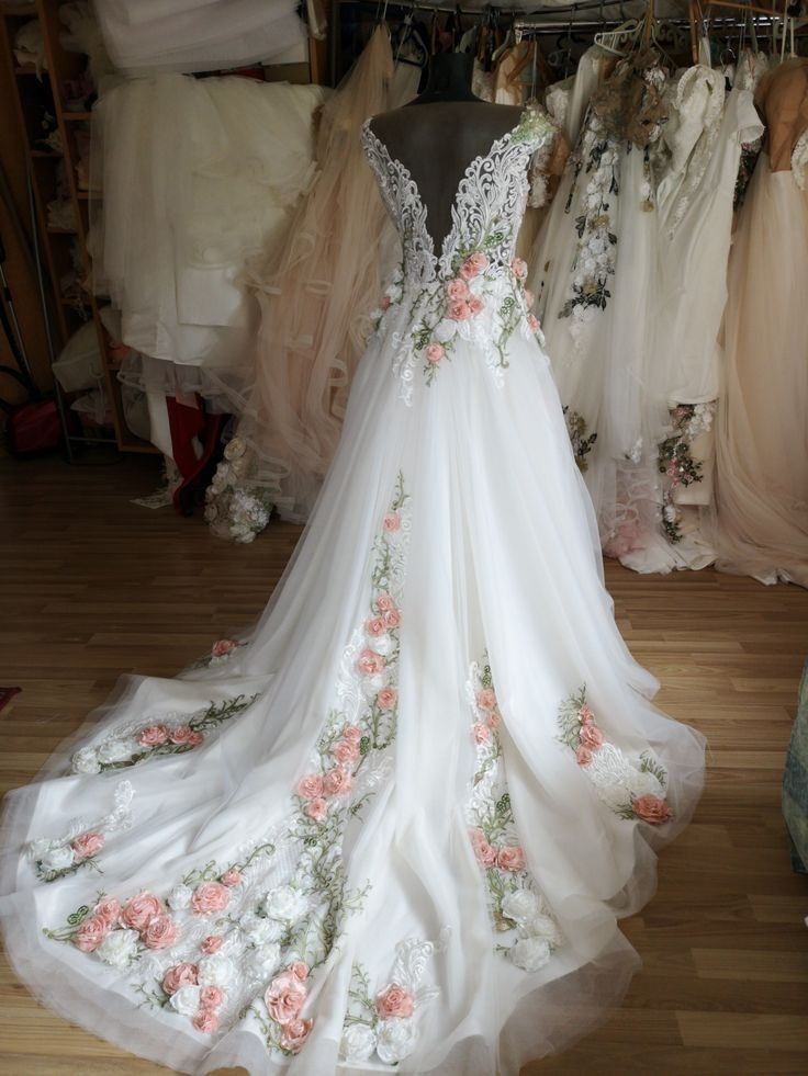 a wedding dress on display in a bridal shop with other gowns behind it