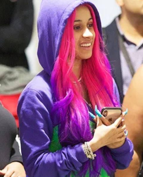 a woman with pink and purple hair is looking at her cell phone while standing next to other people