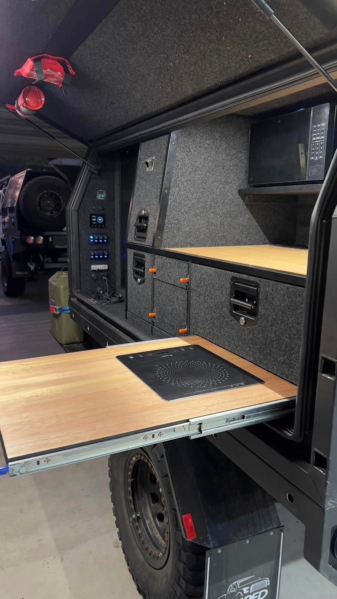 the interior of an rv with wood flooring and black appliances on it's side