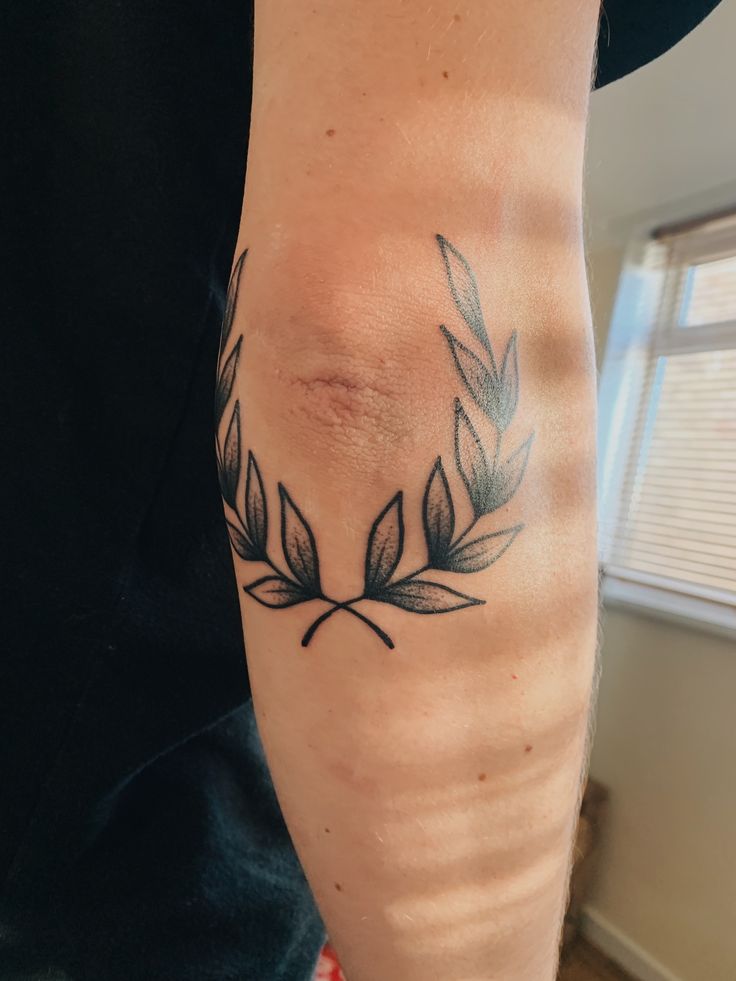 a woman's arm with a tattoo on it that has leaves in the center