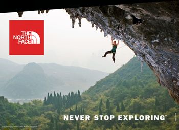 a man climbing up the side of a cliff with trees and mountains in the background