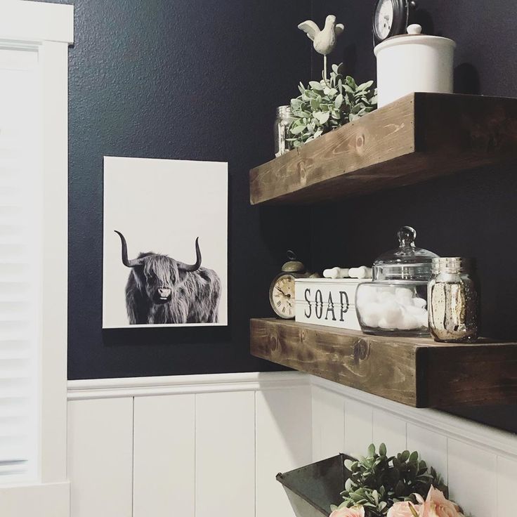 the bathroom is decorated in black and white with flowers on the shelf next to it