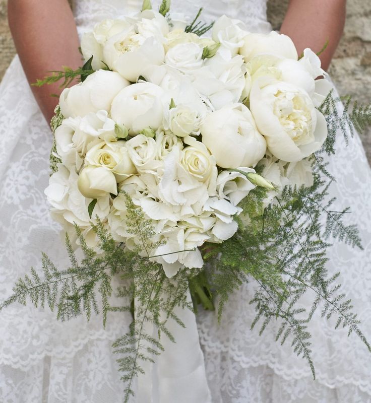 a bride holding a bouquet of white flowers