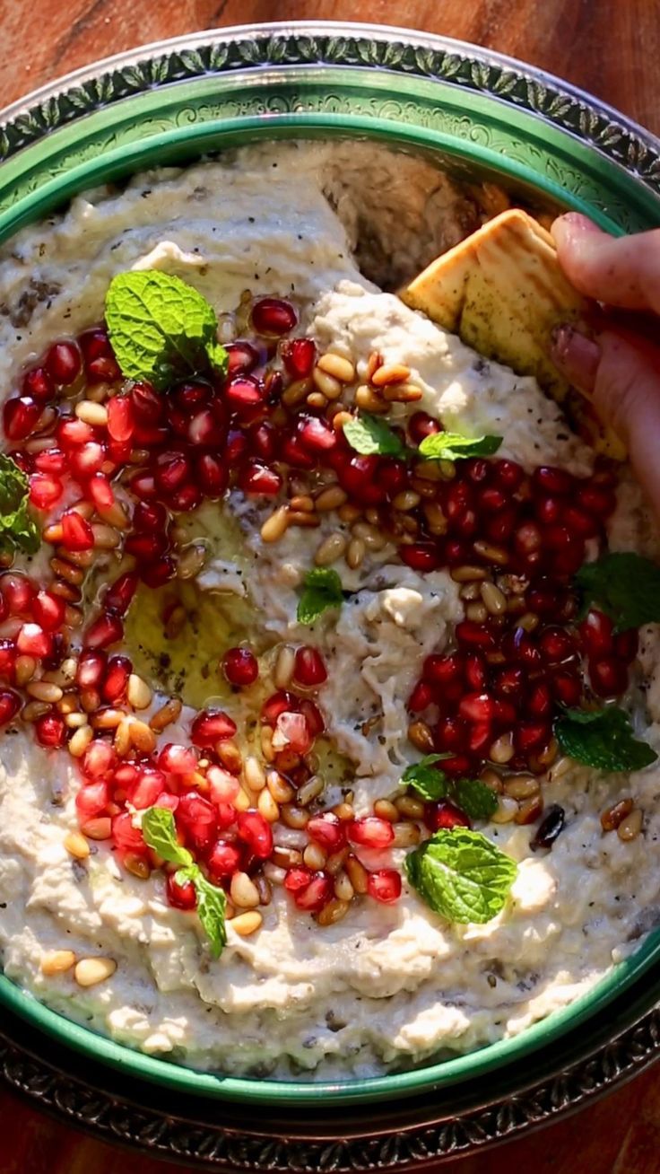 a bowl filled with hummus and garnished with pomegranates