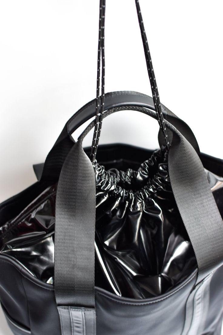 Grab and go. Black neoprene tote bag with a black high shine cinch top closure. With its generous pockets and signature black leather trim, this staple is perfect to be used as your everyday bag, whether jet setting, getting your sweat on, or carrying your baby essentials. Content:- Neoprene- Leather- Imported Size:- Width: 14" - Height: 15.5"- Depth: 7"- Handle Drop: 8.5" Black Waterproof Bags For On-the-go, Black Waterproof Tote Bag, Functional Black Shoulder Bag With Handles, Everyday Waterproof Black Bags, Everyday Black Waterproof Bags, Black Waterproof Shoulder Bag For On-the-go, Black Nylon Shopping Bag, Functional Black Shoulder Bag For Shopping, Sporty Waterproof Black Shoulder Bag