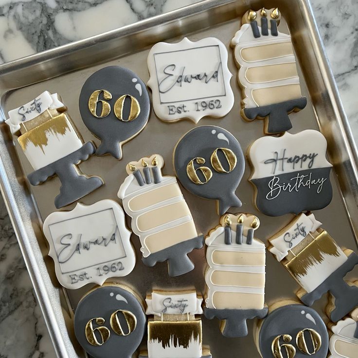 decorated cookies in the shape of 50th birthday cake and candles on a tray with marble background