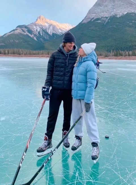 two people are standing on the ice with skis