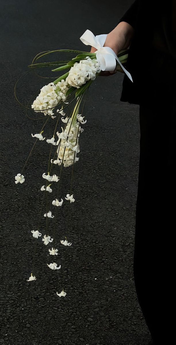 a person is holding flowers on the ground with white petals in their hands and wearing gloves