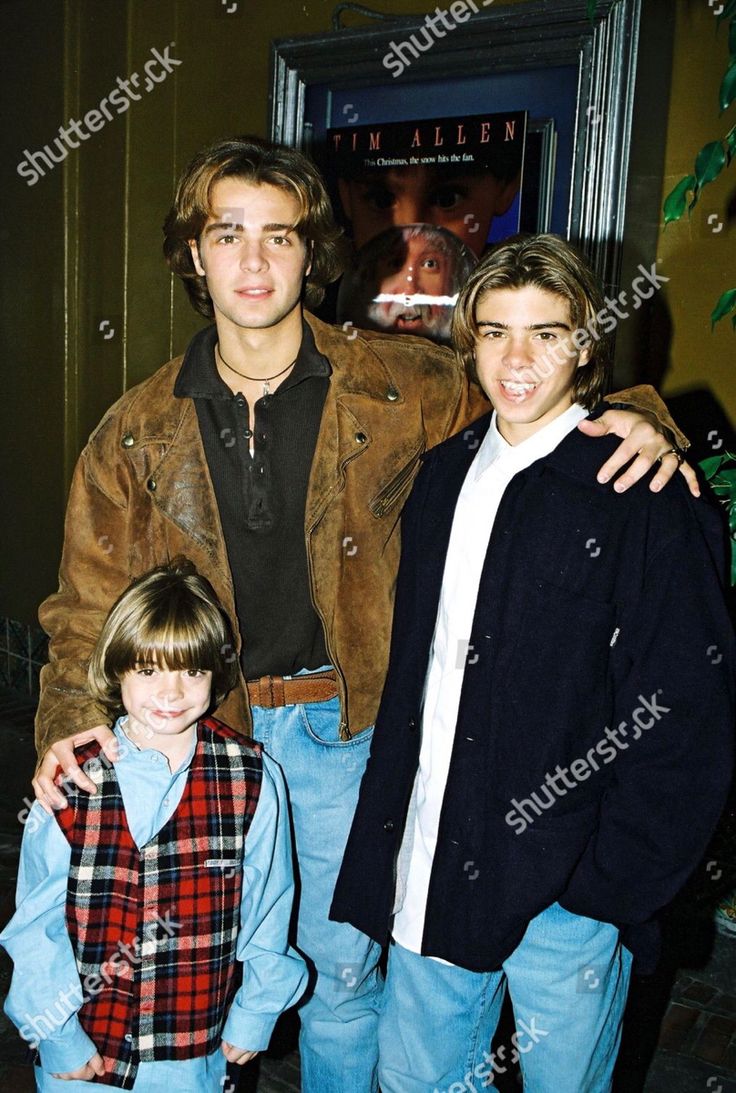 three young men posing for the camera in front of a movie poster at an event