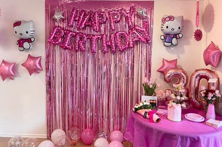 a hello kitty birthday party with balloons, streamers and pink decorations on the wall