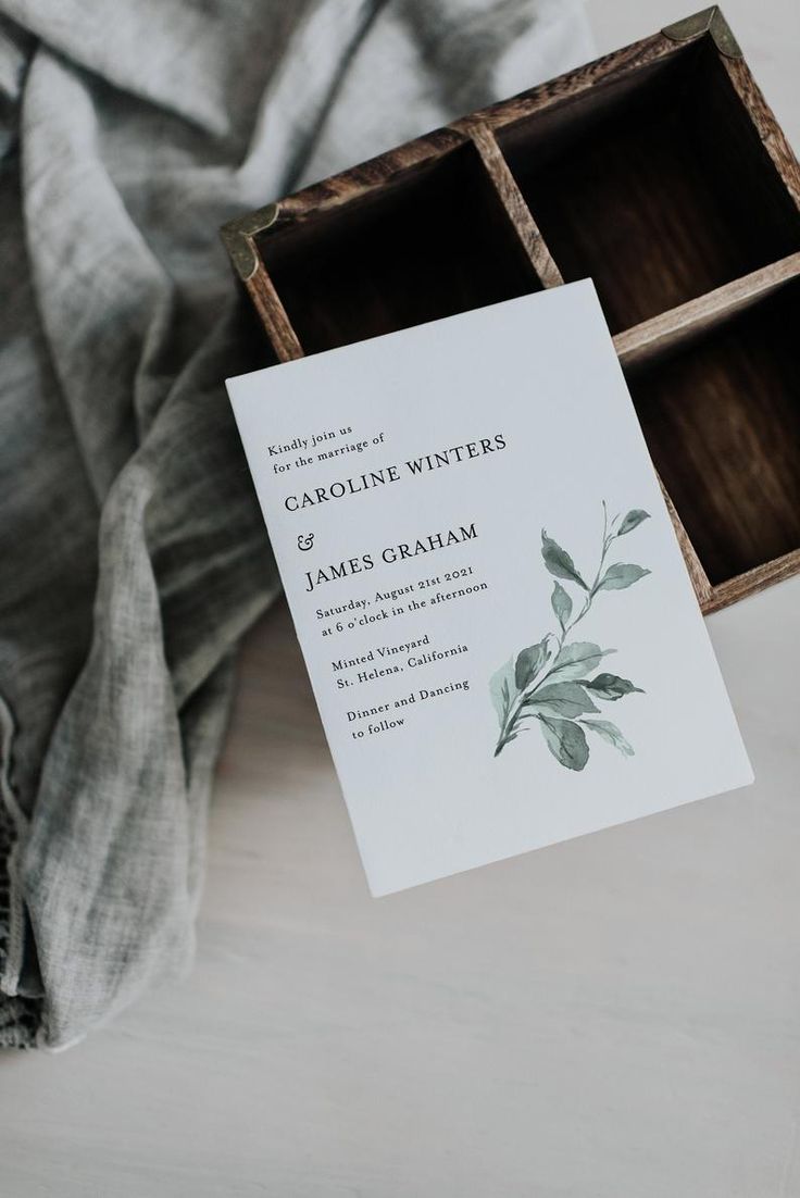 an open wooden box with a wedding card in it on top of a bed next to a blanket