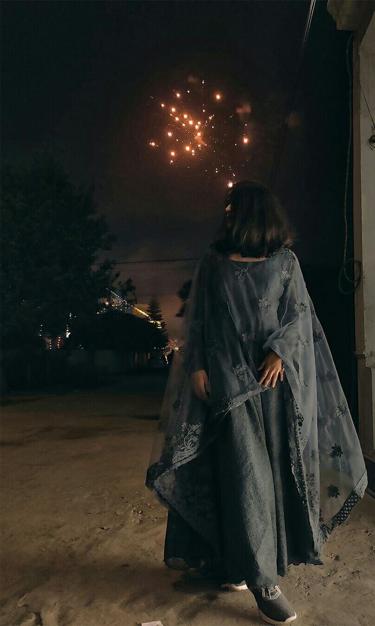 a woman standing in front of a firework display