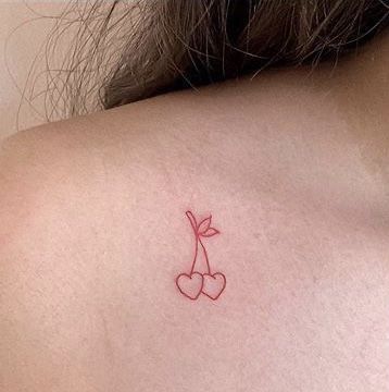 a small tattoo on the back of a woman's shoulder, with cherries