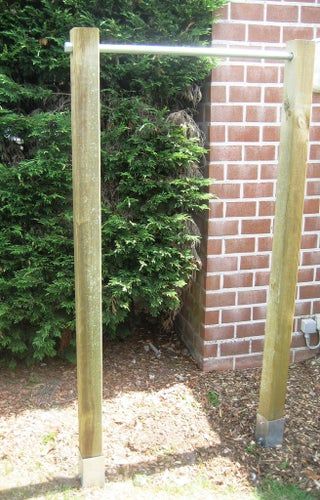 two wooden poles are in front of a brick wall and shrubbery behind the fence