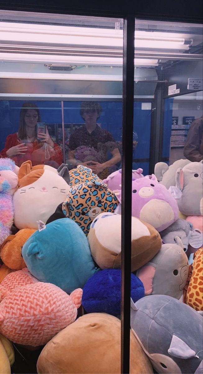 there are many stuffed animals on display in the store window and one person is looking at it