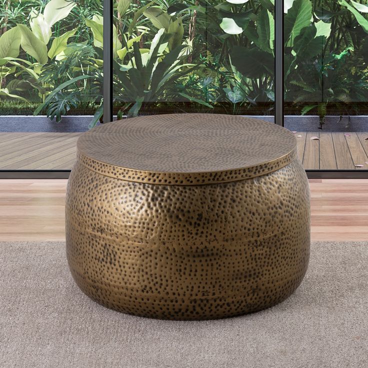 a large round metal table sitting on top of a carpeted floor next to a window