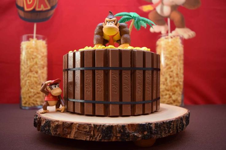 a chocolate cake with monkey figurines on top and other decorations around it in front of a red backdrop