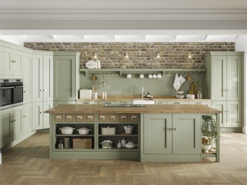 a large kitchen with green cabinets and wooden floors