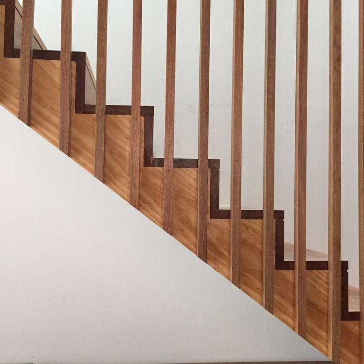 a wooden staircase with white walls and wood handrails