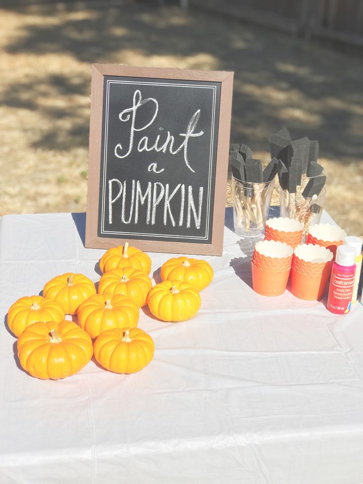 pumpkins are sitting on a table with paint and paper straws in front of them