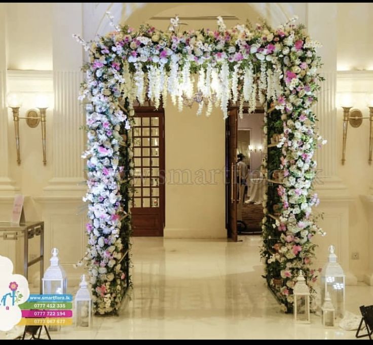 an archway decorated with white and pink flowers in the middle of a hall at a wedding