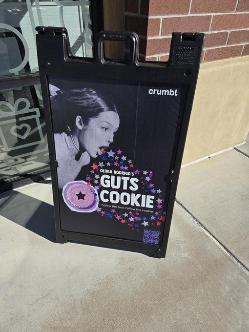 a sign on the side of a building that says guts cookie and has a woman's face painted on it