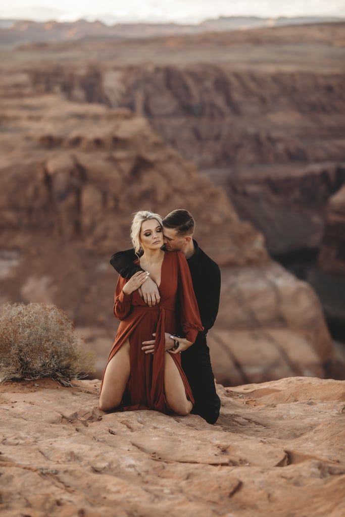 a man and woman sitting on top of a rock in front of the canyons