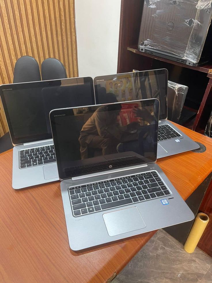 three laptop computers sitting on top of a wooden table