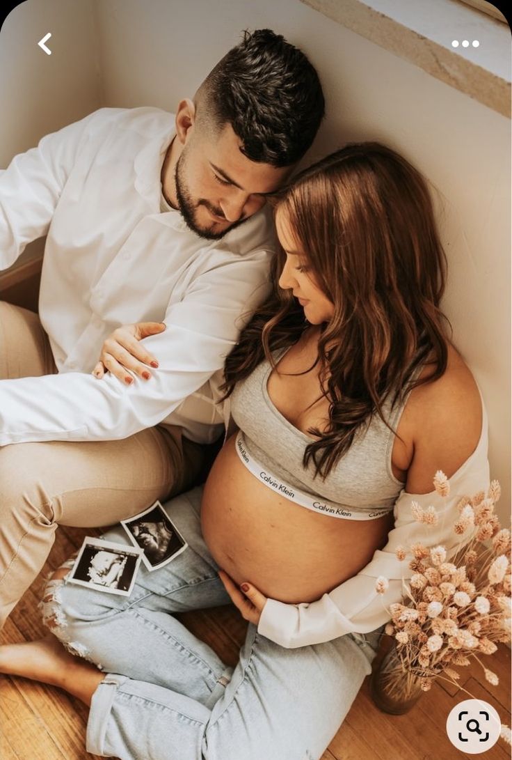 a pregnant couple sitting on the floor together