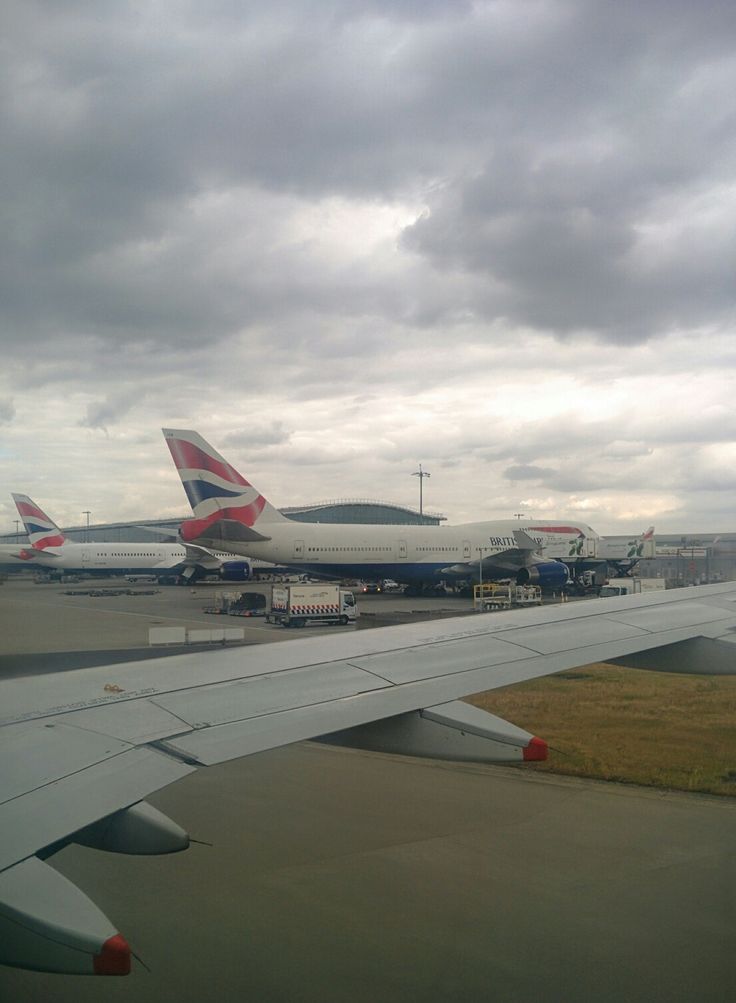 the wing of an airplane as it sits on the tarmac with other planes in the background