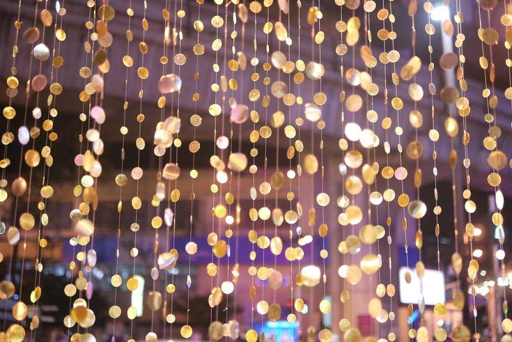 many lights hanging from the ceiling in front of a building at night with blurry background