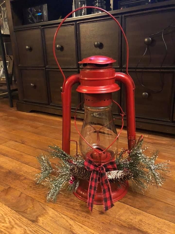 an old red lantern is sitting on the floor in front of a dresser with christmas decorations