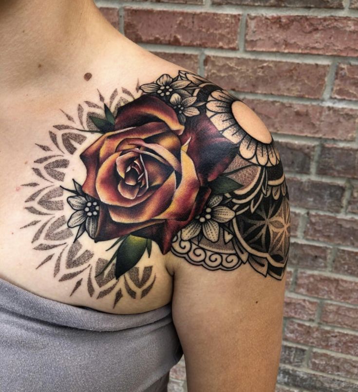 a woman's chest with a rose tattoo on her left shoulder and an intricate design