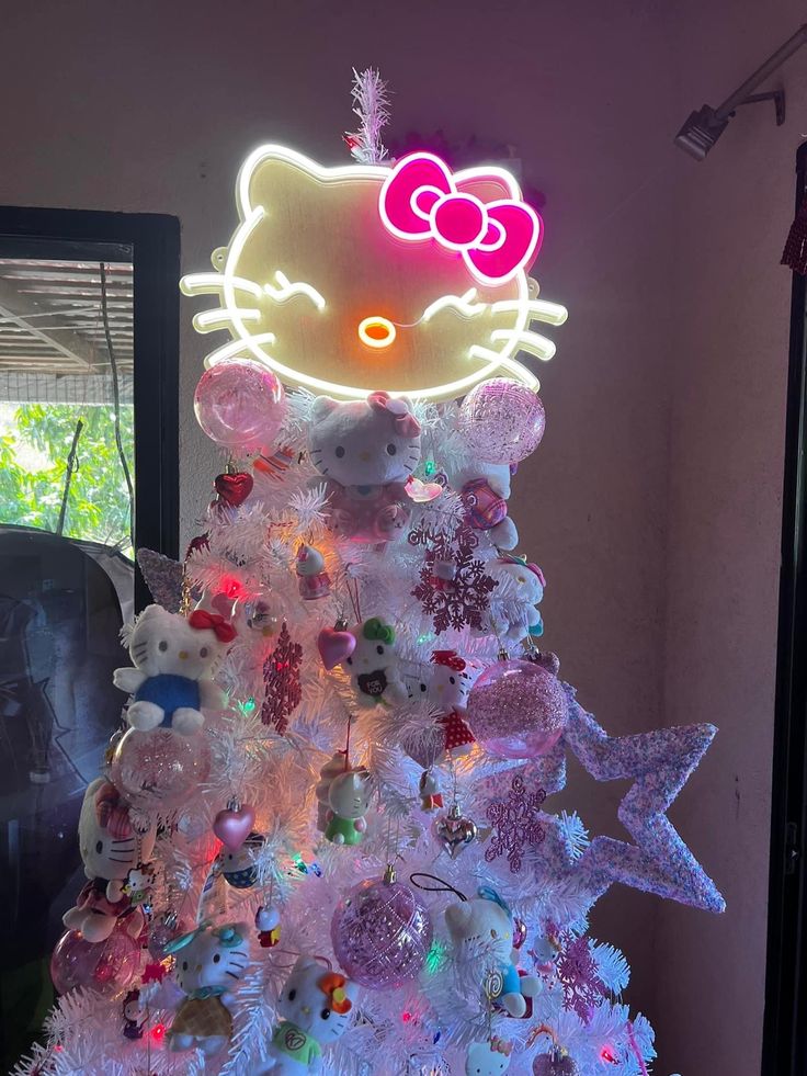 a hello kitty christmas tree with lights and ornaments on the top is decorated in pink, white and purple colors