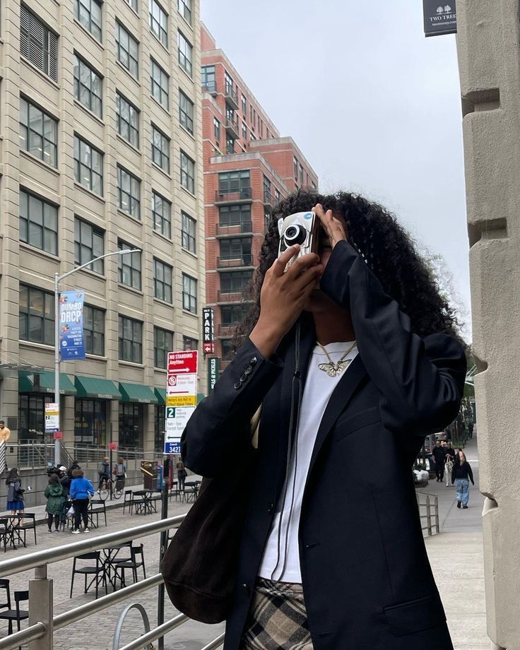 a woman taking a photo with her camera on the sidewalk in front of a building