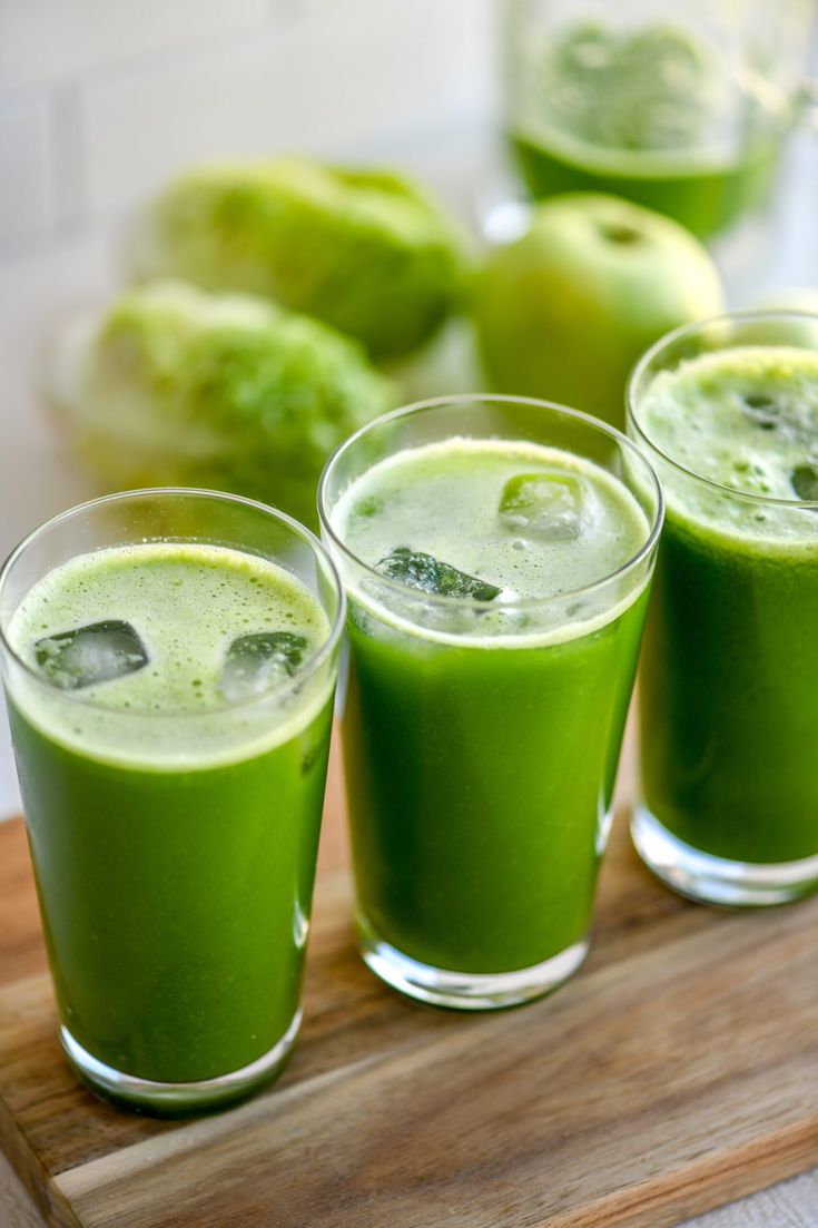 three glasses filled with green liquid on top of a wooden tray