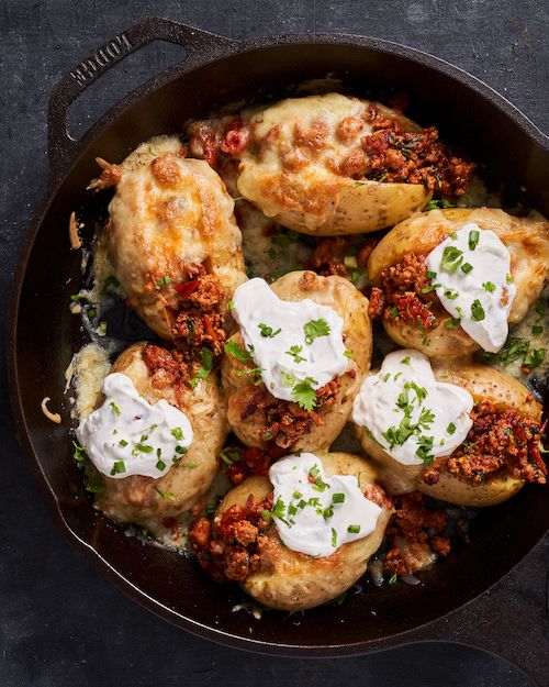 a skillet filled with stuffed potatoes topped with sour cream