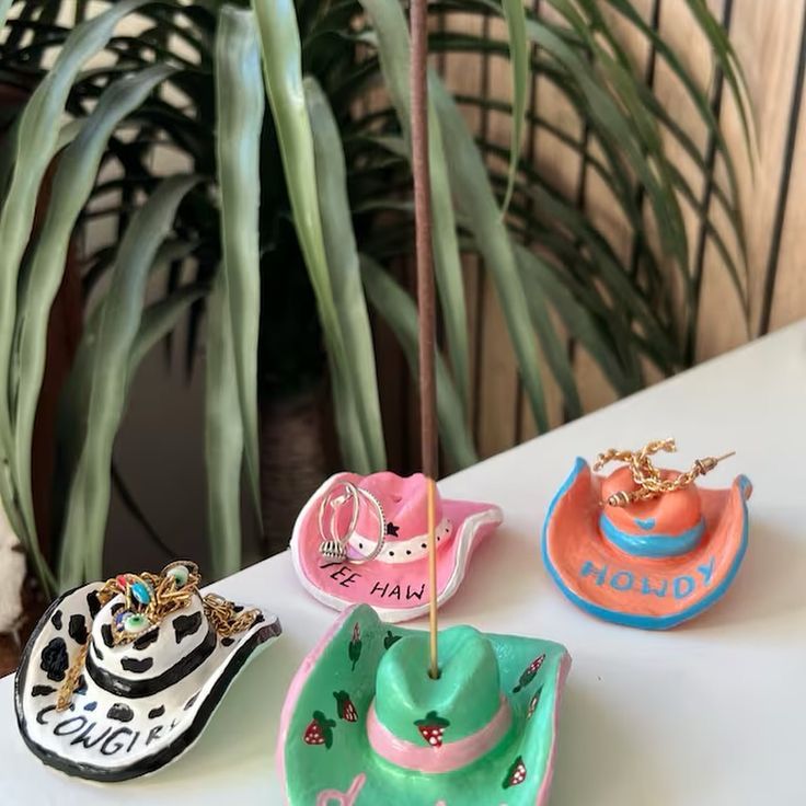 three hats are sitting on a table next to a potted plant and one is wearing a hat