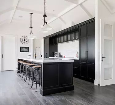 an open kitchen with black cabinets and bar stools