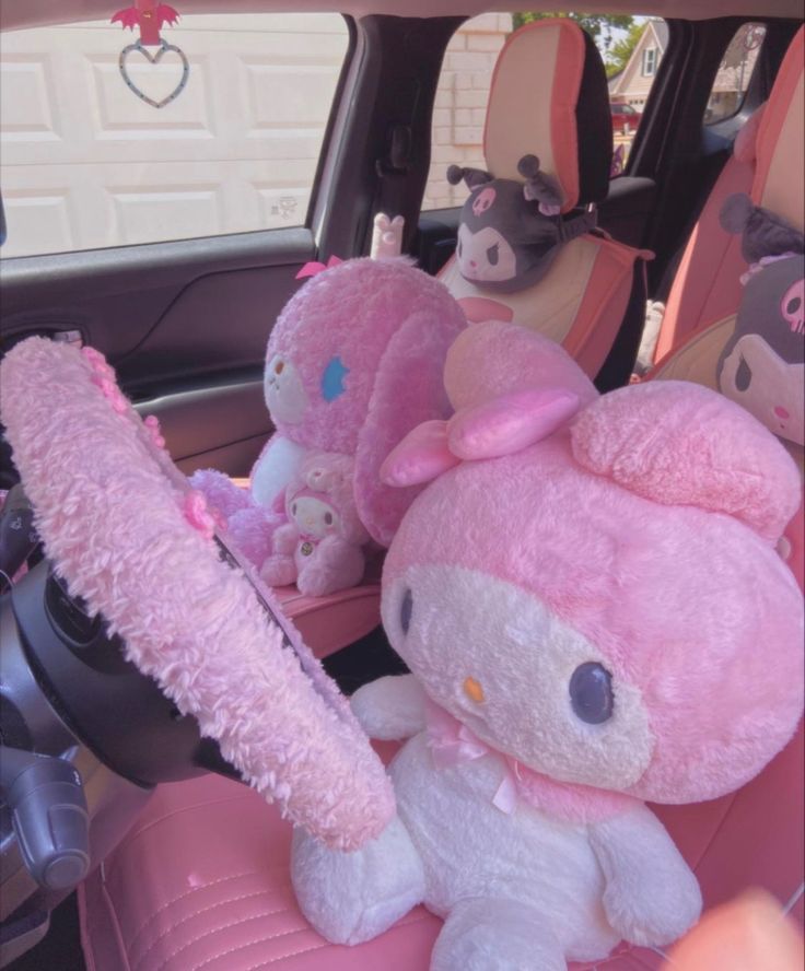 hello kitty stuffed animals sit in the back seat of a car with pink plush seats