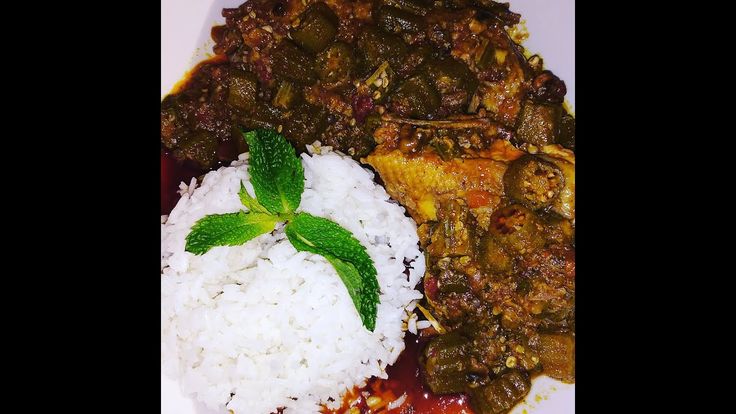 a white plate topped with rice and meat next to green leafy garnish