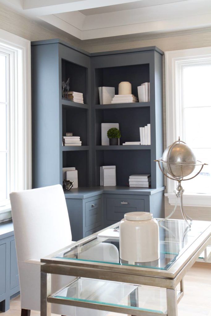 a glass table with white chairs and shelves in the background