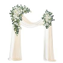 an arch decorated with white flowers and greenery