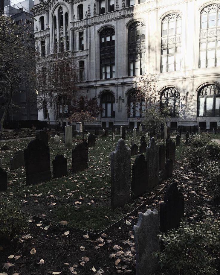 an old cemetery in front of a large building with many headstones on the ground