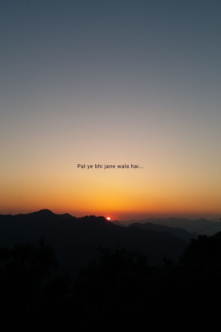 the sun is setting over some hills with trees and mountains in the foreground,