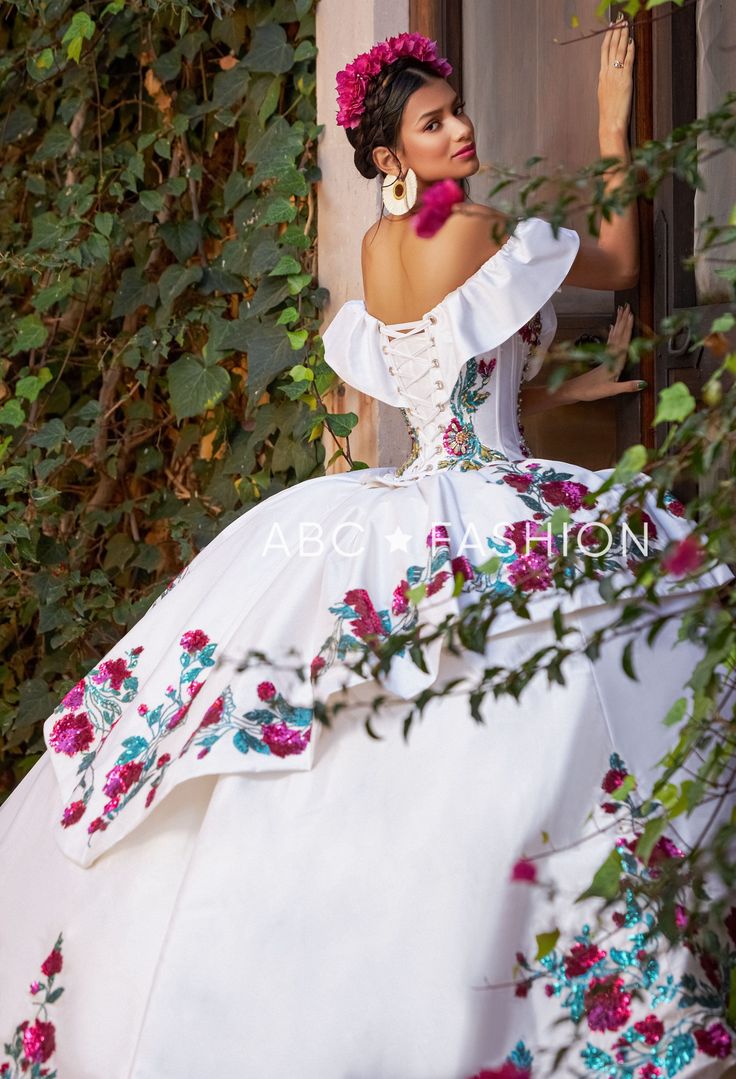 Dance the night away in this floral charro off the shoulder ball gown with A-line split front skirt by Ragazza Fashion M41-141. This beautiful long off the shoulder dress features an illusion V-neck bodice adorned with sequined and beaded floral appliques, short sleeves, open lace-up corset back, and a floor length A-line skirt with a sweep train. Floral Charro Off Shoulder Quinceanera Dress by Ragazza M41-141 Designer: Jazmín Collection by Ragazza Fashion 2023 Style Number: M41-141 Colors: Ivor White Charro Quinceanera Dresses, Quinceanera Dresses Mexican, Split Front Skirt, Vestido Charro, Xv Dresses, Mexican Quinceanera, Mexican Quinceanera Dresses, Quinceanera Themes Dresses, Charro Quinceanera Dresses