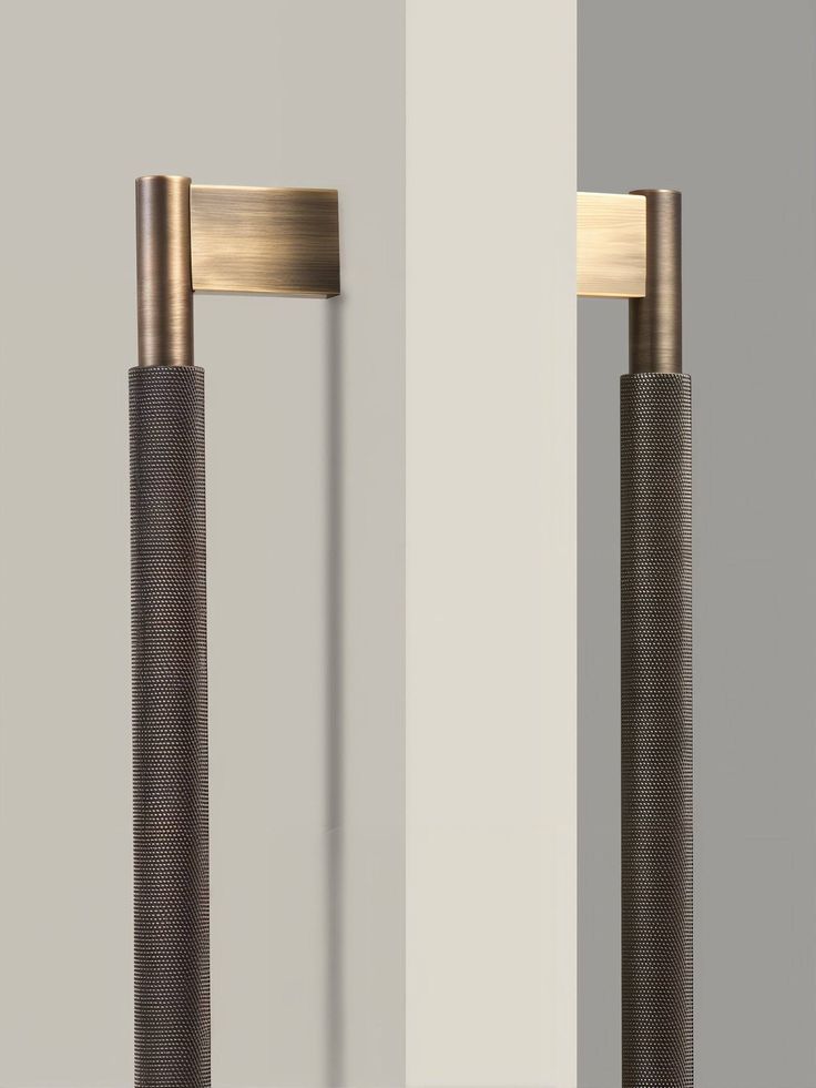 two tall metal poles standing next to each other in front of a white and gray wall