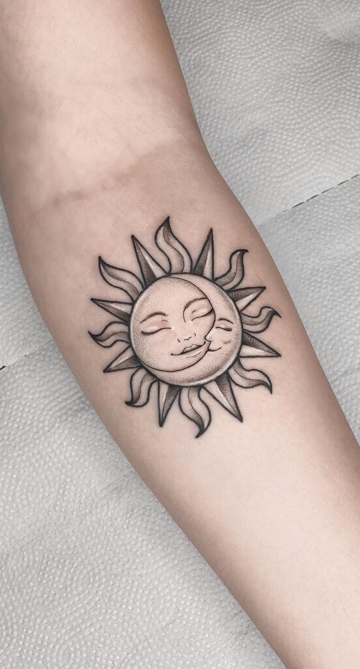 a small sun tattoo on the arm with a sleeping face in front of it's eyes